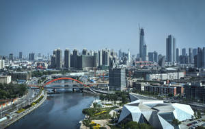 一座現代城市，在清澈的天空下，有一座橫跨河流的紅色橋樑和高樓大廈。 — 唐人街 壁紙