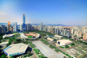 現代城市的鳥瞰圖，有摩天大樓和一個大型體育館。 — 廣州 壁紙