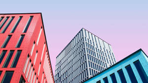 三座現代建築，紅、藍、灰色，襯以粉彩天空 — 現代 壁紙