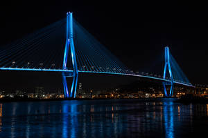 夜晚藍色燈光的吊橋，城市燈光倒映在水中。 — 塔橋 壁紙