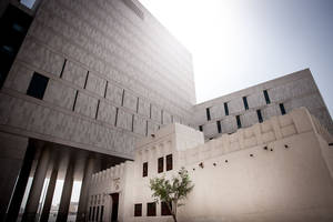 現代混凝土建築聳立於傳統白色結構之上，有小樹。 — 卡達 壁紙