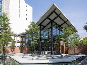 現代玻璃建築，帶有混凝土屋頂，被樹木和水景環繞。 — 咖啡美學 壁紙