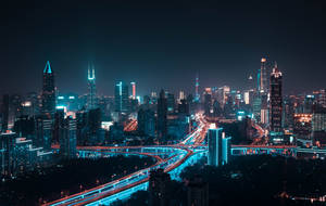 充滿活力的城市夜景，建築物閃閃發光，車輛行駛留下光軌。 — 夜晚 壁紙