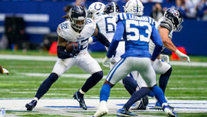 NFL美式足球球員在被防守球員追趕時帶著球奔跑。