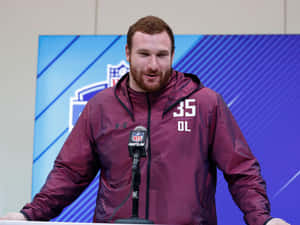 NFL進攻鋒線球員穿著棗紅色外套在新聞發布會上發言。 — 美式足球 壁紙