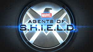 S.H.I.E.L.D.標誌在圓形金屬觀景窗中發出藍光。 — 漫威標誌 壁紙