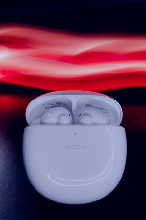 白色 realme 耳機在打開的充電盒中，帶有紅色動態模糊背景。