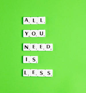 白色 Scrabble 字母磚垂直排列，在亮綠色表面上拼出 'All You Need Is Less'。 — Oppo Find N6 壁紙