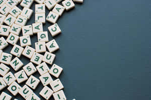 Scrabble 遊戲瓷磚對角排列在有紋理的青綠色背景上。 — MacBook Air M4 壁紙