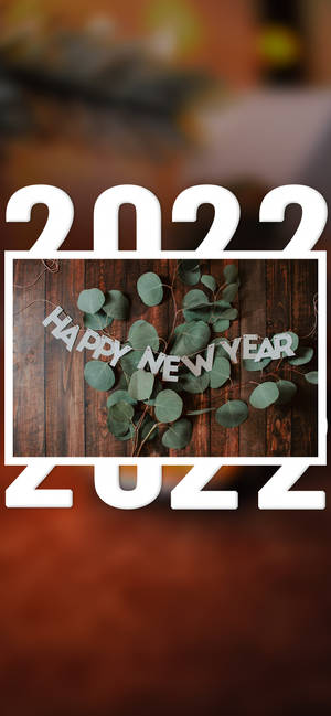 木背景上的Happy New Year 2022標語，配有尤加利葉。 — iPhone 15 Plus 壁紙