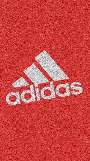 白色Adidas標誌在紋理紅色運動地板上。 — 頂級 iPhone 壁紙