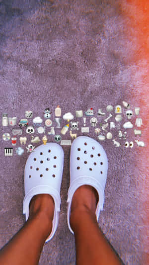 紫色地毯上的白色Crocs，周圍有表情符號貼紙。 — Crocs 壁紙