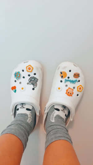 穿著白色Crocs鞋的腳，鞋上有卡通飾物和灰色貓咪襪子。 — Crip 壁紙