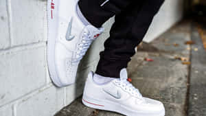 白色Nike Air Force 1運動鞋，帶有紅色點綴，背景為混凝土牆。 — 球鞋 壁紙