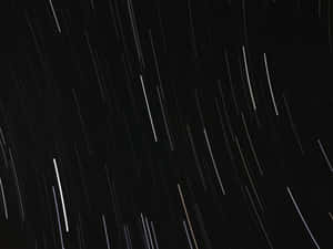星軌在長時間曝光照片中劃過夜空。 — 黑色 壁紙
