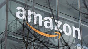玻璃建築上的Amazon標誌，前面有光禿禿的樹枝。 — 亞馬遜 GIF 壁紙