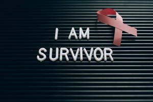 深色板上的白色字母寫著 I AM SURVIVOR，附紅色絲帶 — 桌面 壁紙