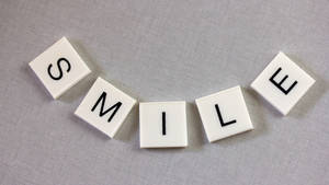 灰色布料上帶有黑色字母拼出 smile 的白色瓷磚。 — 魯夫微笑 壁紙