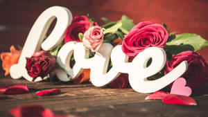 白色 'love' 字母被紅粉玫瑰環繞在木桌上。 — 花朵 4K 壁紙