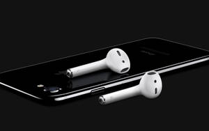 白色無線耳塞放在黑色智慧型手機上，背景深色。 — AirPods 壁紙