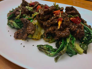 白色盤子上的滋滋作響牛肉和烤焦蔬菜，搭配紅辣椒和黑芝麻。 — Burberry 壁紙