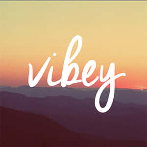 日落時紫色山脈上方的白色草書文字 vibey — 海灘度假 壁紙
