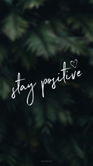 stay positive 勵志文字，心形圖案在深綠色樹葉背景上。 — 正向 壁紙