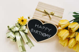 心形黑板上帶有黃色鬱金香和禮物盒的生日祝福訊息。 — Tumblr 花朵 壁紙
