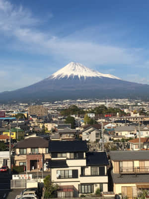 從日本城鎮的屋頂和晴朗的天空看到的積雪富士山。 — iPad Air 壁紙