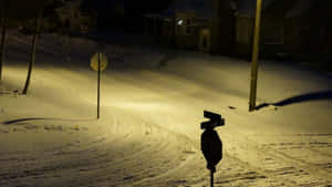 夜晚積雪的街道，路燈下有停車標誌和房屋。 — Pro Display XDR 壁紙
