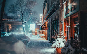夜晚積雪的城市街道，咖啡館燈光閃爍，車輛停泊。 — 冬季風景 壁紙