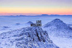 日出時分的雪山景觀，帶有 Love Moschino 文字疊加。 — 雪山 壁紙