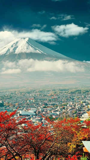富士山頂覆蓋白雪，俯瞰著被秋葉紅樹環繞的城市。 — 舊金山 iPhone 壁紙