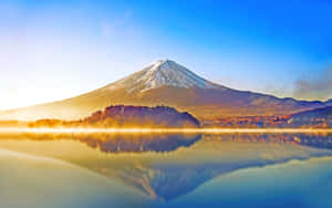 富士山倒映在霧氣繚繞的湖面上，日出時分金色光芒。