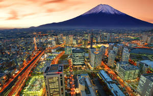 富士山俯瞰著日落時分閃爍的城市和流動的車燈。 — 東京卍复仇者 壁紙