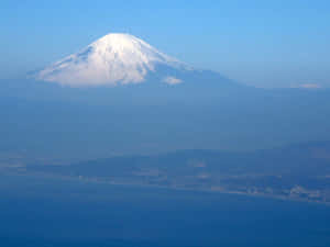 從上方俯瞰白雪皚皚的富士山，下方是沿海城鎮。 — 富士山 壁紙