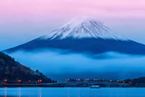 富士山在暮色中帶有雪和霧，倒映在水中，有一座亮燈的橋樑。 — 富士山 壁紙