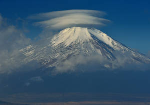 白雪覆蓋的富士山，山頂上方有透鏡狀雲，背景是清澈的藍天。 — 富士山 壁紙