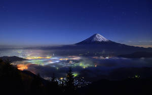 夜晚的富士山，下方是城市燈光，上方是星星 — 富士山 壁紙