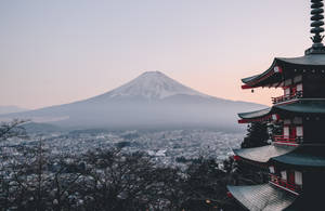 從寶塔眺望黎明時分霧氣籠罩的城市上方的雪覆蓋富士山