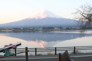 富士山倒映在黎明時分的湖中，有光禿的樹枝和路邊欄杆。 — 富士山 壁紙