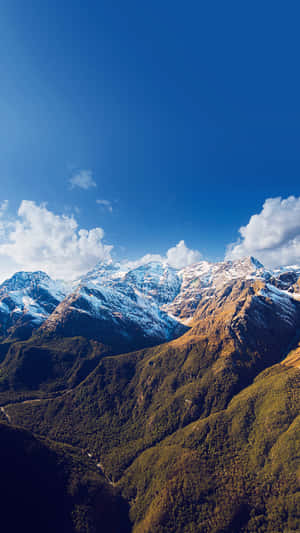 晴朗藍天下白雪覆蓋的山脈，下方是綠色山谷 — 山脈 壁紙
