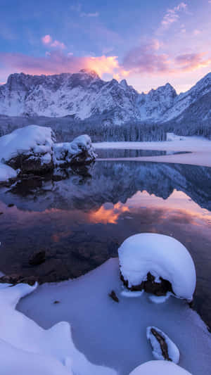 白雪覆蓋的山脈在日落時分倒映在冰凍的湖面上。 — 冬季風景 壁紙