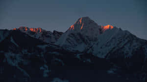 白雪皚皚的山脈在黃昏時分沐浴在金色的夕陽餘暉中。 — 山脈 壁紙