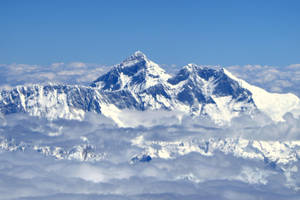 白雪覆蓋的山峰聳立在厚厚的雲層之上。 — 雲朵 GIF 壁紙