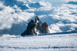 一座城堡位於白雪覆蓋的山峰頂端，聳立在雲海之上。 — 寒冷 壁紙