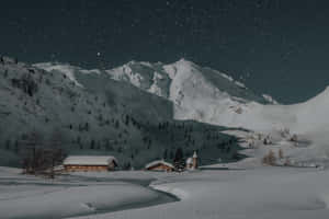 白雪覆蓋的山村，星空下木屋和松樹。 — 冬季房屋 壁紙
