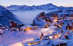 黃昏時分，白雪覆蓋的山村亮起燈光，霧氣在山谷中翻滾。 — 雪山 壁紙