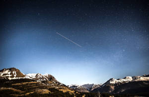繁星夜空下的雪山山脈，帶有流星軌跡。 — 高解析度 壁紙