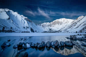 冰凍的湖面倒映著繁星夜空下的雪山。 — 冬季風景 壁紙